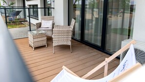 A balcony with wicker furniture, a glass door, and a view of the outside. - Air-conditioned Apartment, Indoor Pool, Sauna (Dziwnów)