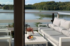 Ein Balkon mit einer weißen Couch, einem kleinen Tisch mit Obstschale und einer Topfpflanze.