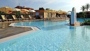 A swimming pool with clear water, surrounded by sun loungers and umbrellas. - Apartment in Tuscany Near Sandy Beaches (Rosignano Marittimo)