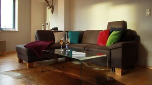 A modern living room with a brown leather sofa, a glass coffee table, and a fur rug. - Apartment in Gustrow Near Inselsee Lake (Guestrow)