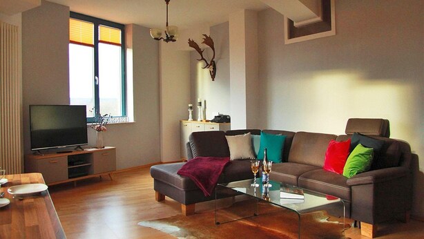 A modern living room with a sofa, coffee table, and TV. - Apartment in Gustrow Near Inselsee Lake (Guestrow)