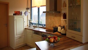 A kitchen with a wooden countertop, a built-in oven, a coffee maker, and a fruit bowl. - Apartment in Gustrow Near Inselsee Lake (Guestrow)