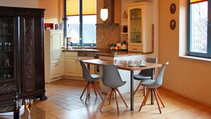 A modern kitchen with a dining area, wooden cabinets, and a view of the outside through large windows. - Apartment in Gustrow Near Inselsee Lake (Guestrow)