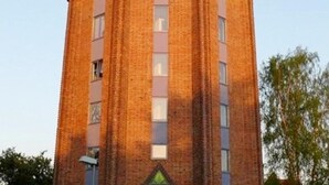 A tall, red brick building with a central entrance and multiple windows. - Apartment in Gustrow Near Inselsee Lake (Guestrow)