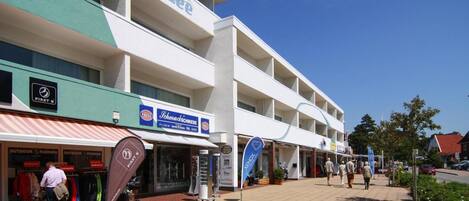 A multi-story building with various shops on the ground floor, including outdoor fashion and a fossil store.