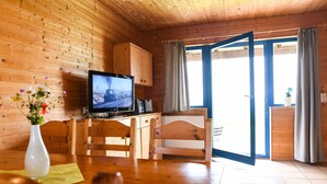 A wooden interior with a dining table, chairs, a television, and a kitchen area. - Ferienpark Harz in Hasselfelde (Oberharz am Brocken)