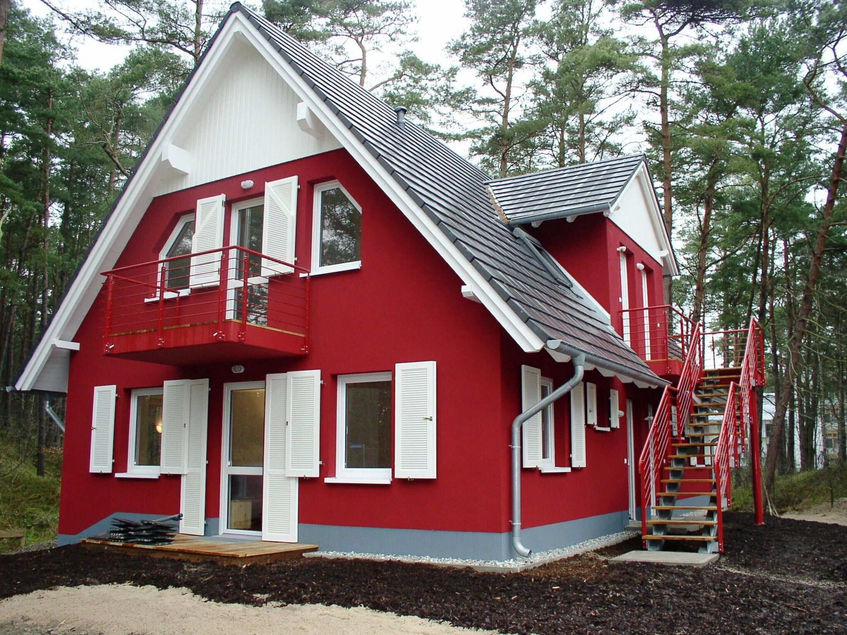 A red two-story house with white shutters, a balcony, and a red staircase.