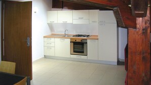 A compact kitchen with white cabinets, a stove, and an oven.