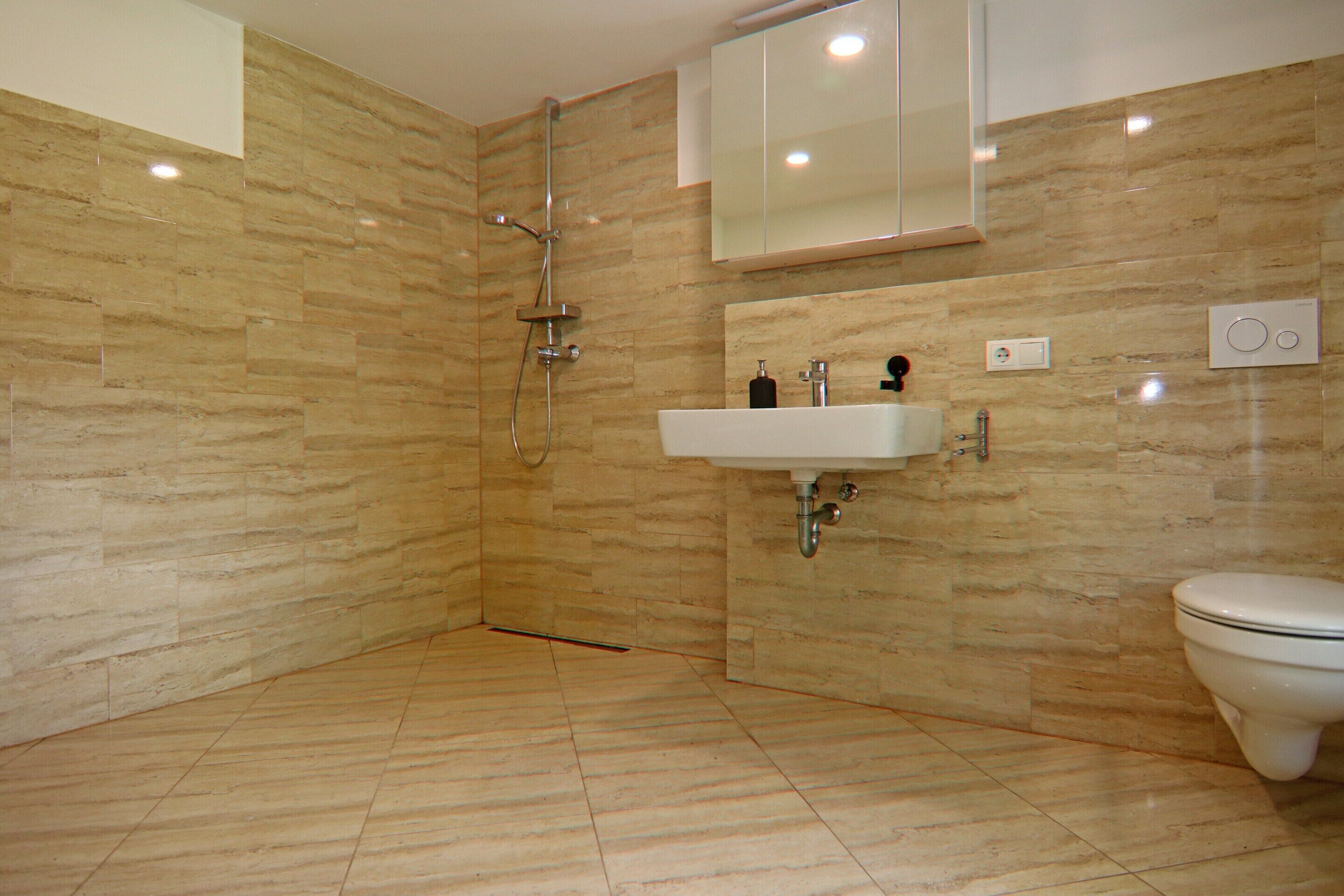 A modern bathroom with a shower, sink, and toilet.