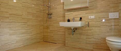 A modern bathroom with a shower, sink, and toilet.