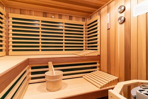 A wooden sauna with benches and a bucket. - Ferienhaus mit Sauna in St.peter-ording (St. Peter-Ording)