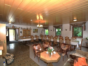 Un espace repas avec des tables et des chaises en bois, une cheminée et une vue sur l’extérieur.