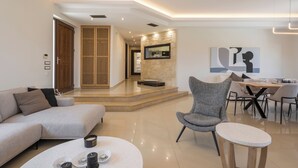 A modern living room with a sofa, a round coffee table, and a dining area with a table and chairs. - Villa Wisdom (Chania)
