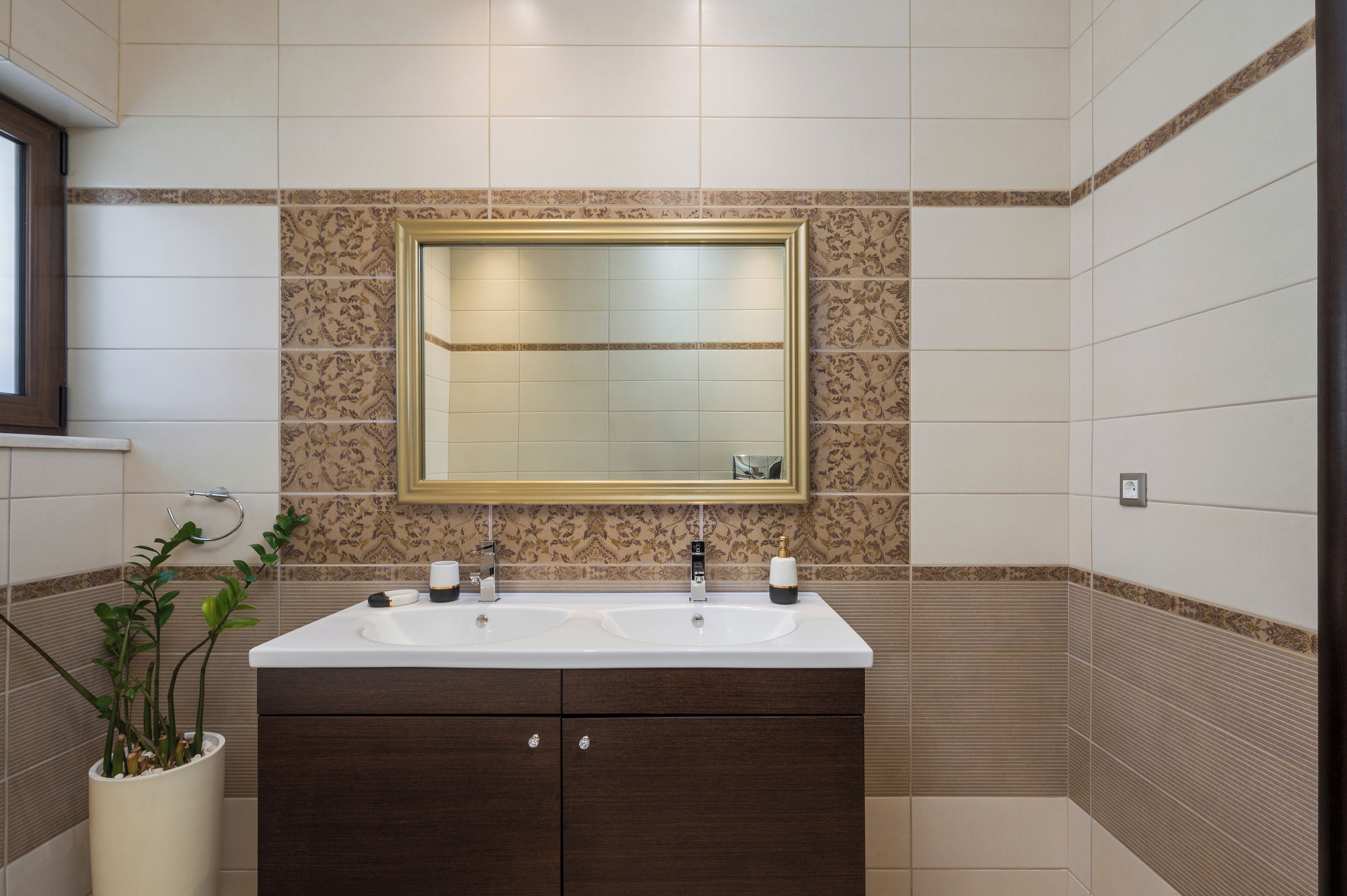 Un baño con dos lavabos, un espejo grande y una planta en maceta.