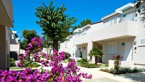 Un immeuble résidentiel doté d’une cour intérieure, de murs extérieurs blancs et d’un arbre aux fleurs violettes.
