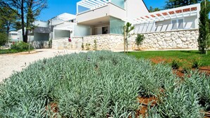 Une villa moderne dotée d’un mur en pierre, d’un patio couvert et d’un jardin bien entretenu.