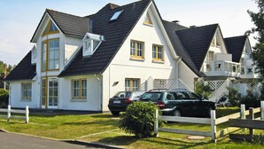 Une maison à deux étages, dotée d’un toit à forte pente, d’une lucarne et d’un balcon. Deux voitures sont garées dans l’allée.