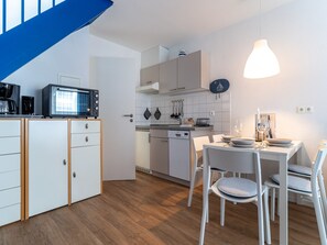 Une cuisine compacte avec des meubles blancs, un four à micro-ondes et un coin repas comprenant une table et des chaises.