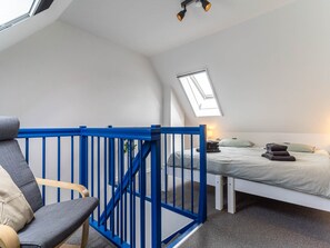 A bedroom with a skylight, a bed, a chair, and a blue railing. - Ferienwohnung in St. Peter-ording (St. Peter-Ording)