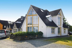 A two-story house with a steeply pitched roof, large windows, and a stone wall in front. - Ferienwohnung in St. Peter-ording (St. Peter-Ording)