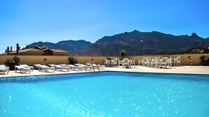 Piscina con sillas de descanso y una vista de montaña al fondo.