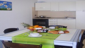 Una mesa de comedor con mantel verde, un tazón de fruta y diferentes condimentos.