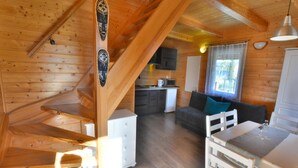 A wooden cabin interior with a staircase, a kitchen area, a dining table, and a sofa. - Cottage in Ustronie Morskie Near Beach (Ustronie Morskie)