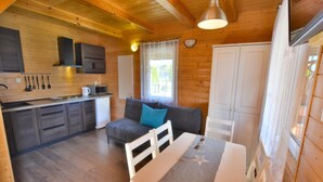 A cozy cabin interior with a kitchenette, a dining area, and a sofa. - Cottage in Ustronie Morskie Near Beach (Ustronie Morskie)
