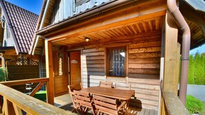 A wooden cabin with a wooden deck and a table and chairs set up outside. - Cottage in Ustronie Morskie Near Beach (Ustronie Morskie)