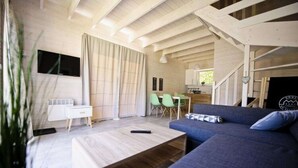 A modern living room with a sofa, a coffee table, and a dining area with chairs. - Holiday Home Pobierowo Near Baltic Sea (Rewal)
