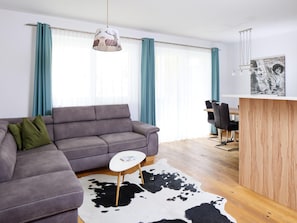 Un salon moderne avec un canapé gris, une petite table blanche et un tapis en peau de vache.