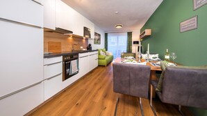 A modern kitchen with white cabinets, a wooden countertop, and a dining area with a table set for two. - Apartment in Neukirchen by Wildkogelbahn (Neukirchen am Grossvenediger)