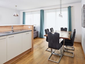 A modern kitchen with a wooden countertop, a sink, and a dining area with a table and chairs. - Apartment in Neukirchen by Wildkogelbahn (Neukirchen am Grossvenediger)