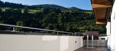 Un balcon donnant sur une vallée verdoyante et des collines.