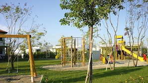 Un parque infantil con diversas estructuras de juego, rodeado de césped y árboles.