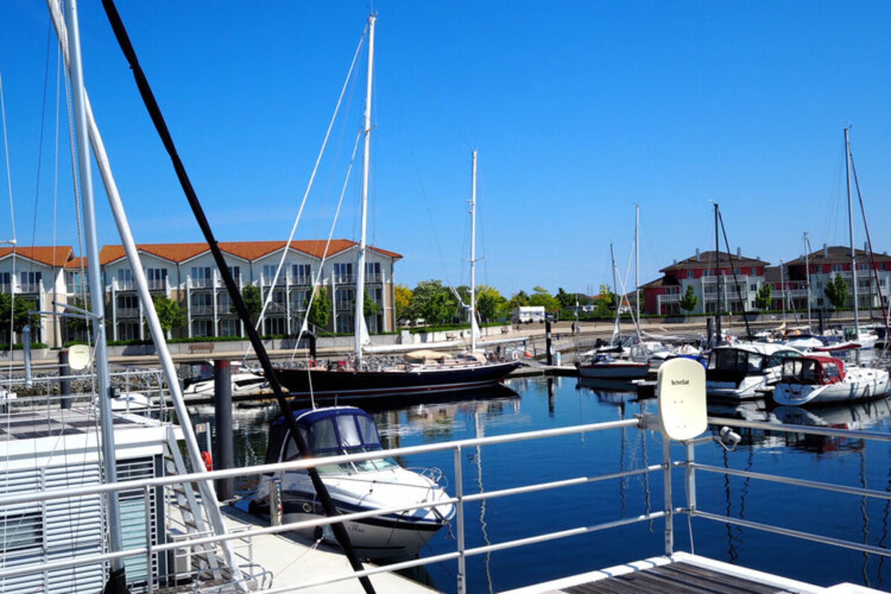 A marina with boats docked, a clear sky, and buildings in the background.