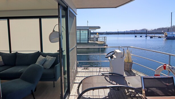Un balcon moderne avec un canapé, une chaise et une petite table.