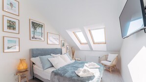 A bedroom with a bed, a nightstand, a chair, and skylights. - Comfortable 2-room Apartment, Grzybowo (Kolobrzeg)
