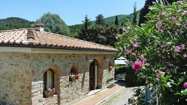 A stone building with a tiled roof, arched windows, and a bench outside. - Rustic House in Tuscany With Shared Pool (San Giuliano Terme)