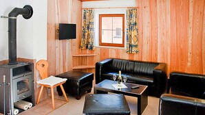 Een gezellige woonkamer met een open haard, lederen meubels en een aan de muur bevestigde televisie.