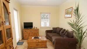 A living room with a brown sofa, wooden cabinet, and a television. - Wohnung in Lubben im Spreewald fur 4 Personen (Lübben (Spreewald))