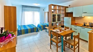 Une chambre d’hôtel compacte comprenant un coin cuisine, un espace repas et deux lits simples.