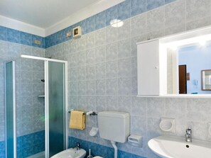 Une salle de bain avec une douche à parois de verre, un lavabo, des toilettes et un miroir.