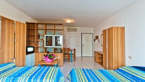Une chambre avec deux lits, un bureau avec une chaise, une télévision et une armoire.