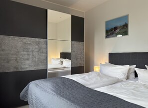 A modern hotel room with a large bed, a mirror, and a painting on the wall. - Apartment in Harz Near Brocken Railway (Wernigerode)