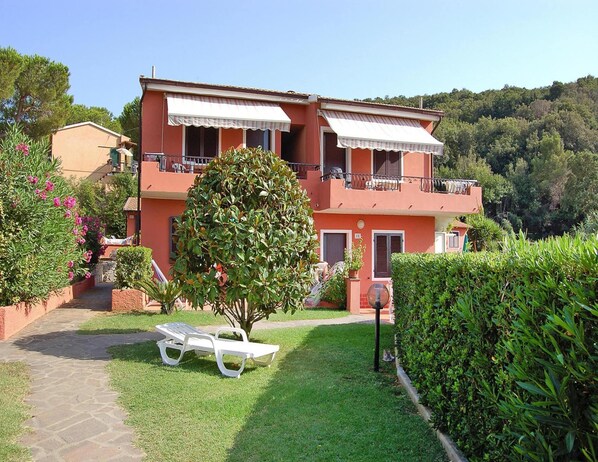 Relax in a serene garden setting with a well-maintained lawn and a balcony overlooking the lush hillside.
