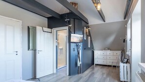 A bedroom with a bed, a white dresser, a desk with a laptop, and a shower area. - Wundervolles Ferienhaus fur Tating (Tating)