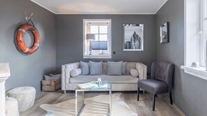 A modern living room with a sofa, armchair, glass coffee table, and a unique rug. - Wundervolles Ferienhaus fur Tating (Tating)