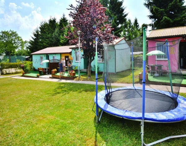 A trampoline in a grassy yard with a house in the background. - Bungalow Close to the Beach, Sianozety (Ustronie Morskie)