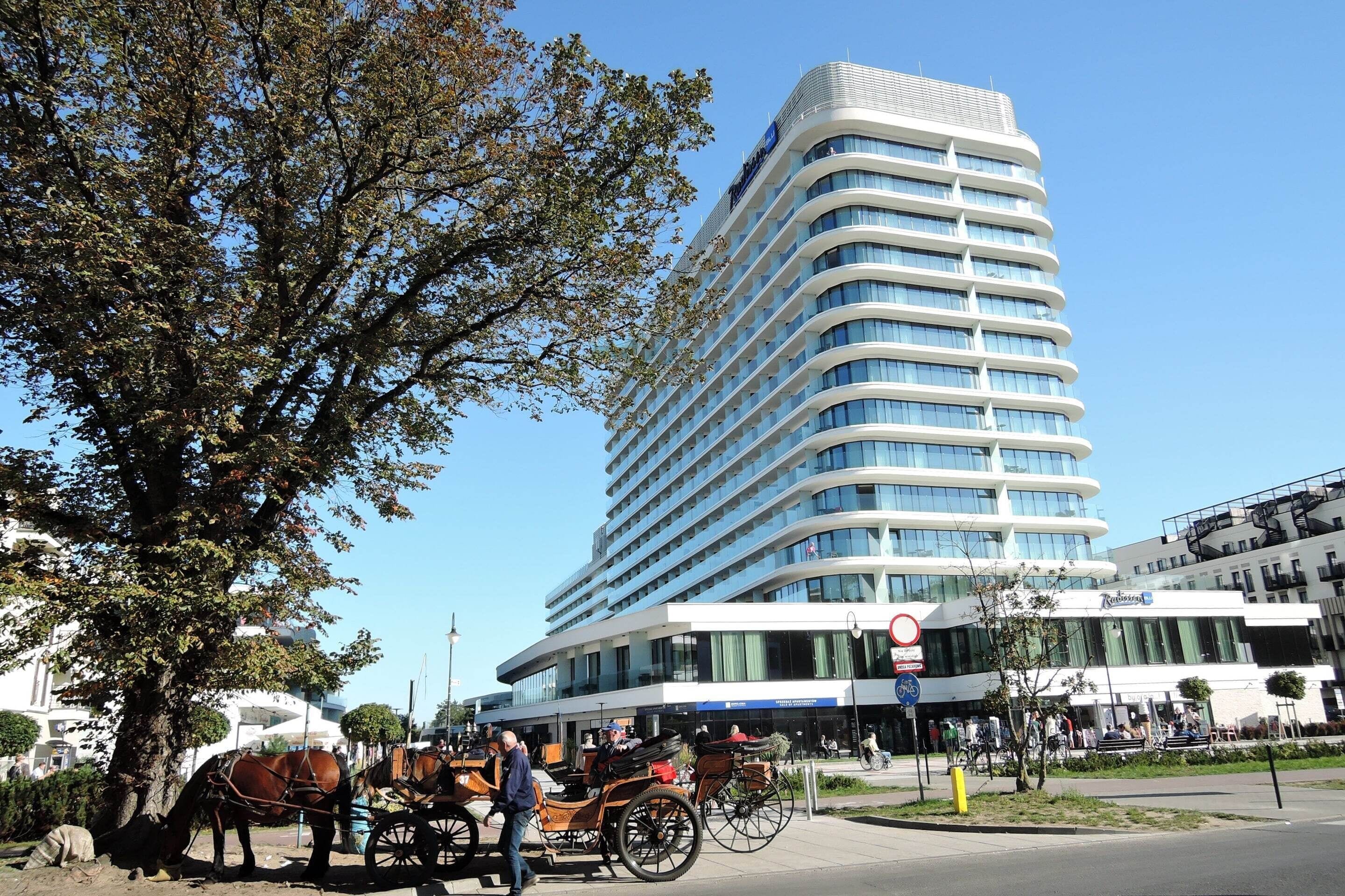 Ein modernes Hotel mit gebogener Fassade, großen Fenstern und einer auffälligen Beschilderung.
